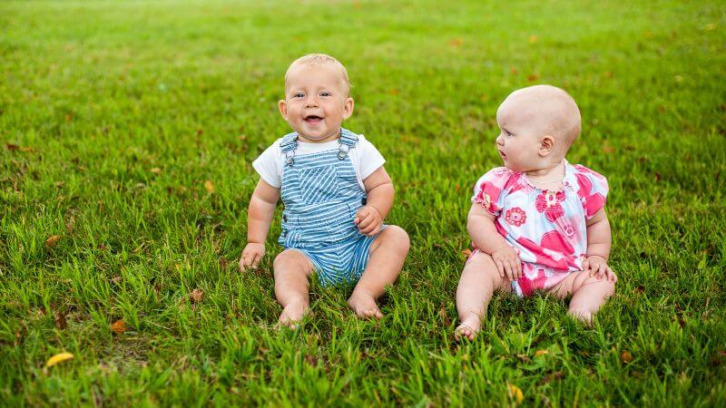 Baby boy and bay girl sitting on grass